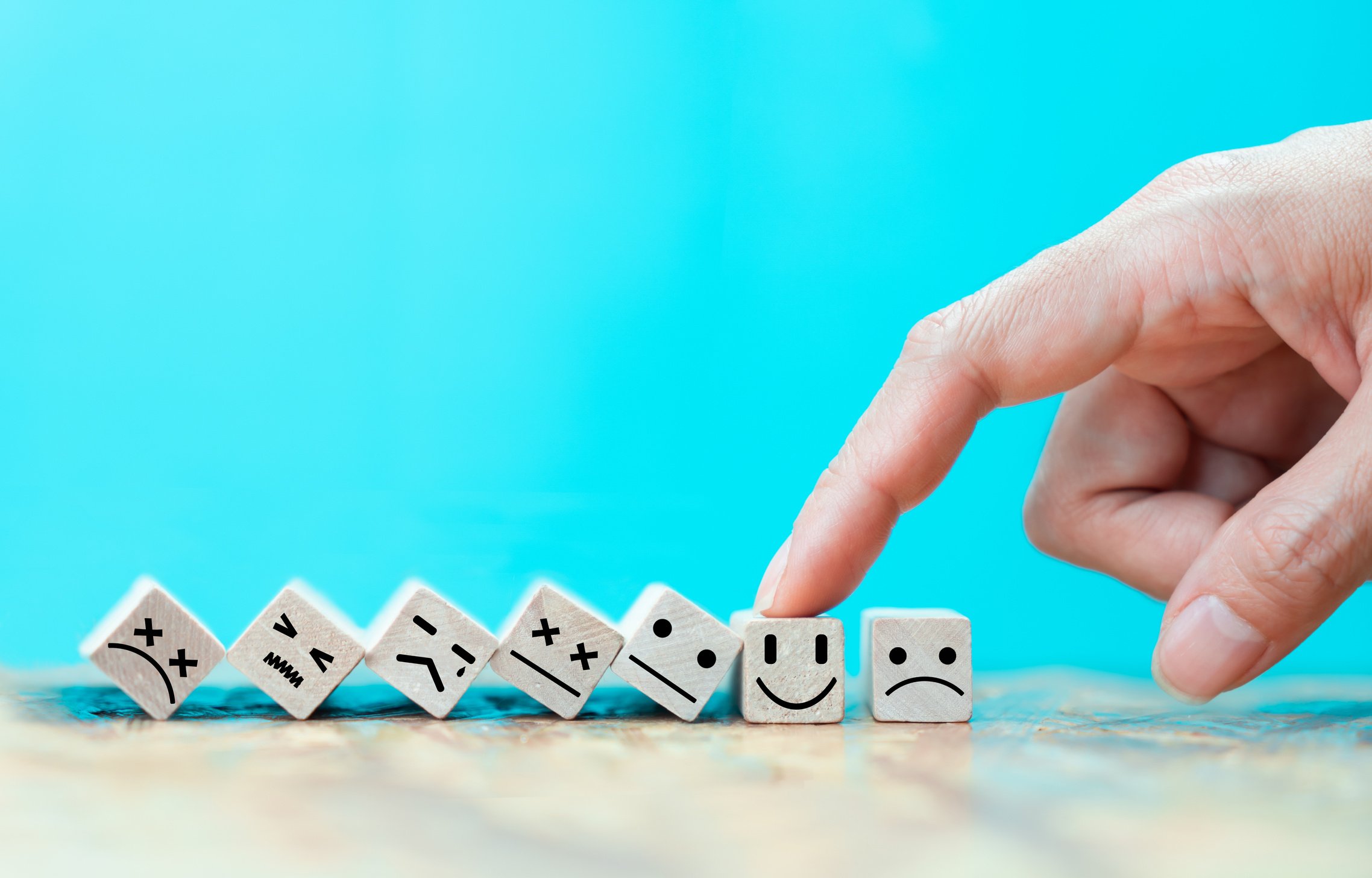 Businessman chooses a happy emoticon icons face on wooden block.